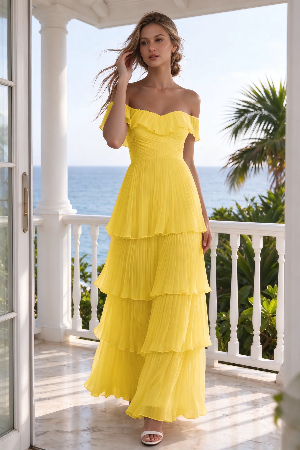 Outdoor front view on a seaside terrace of Seraphina yellow tiered ruffle maxi dress with a long flowing skirt