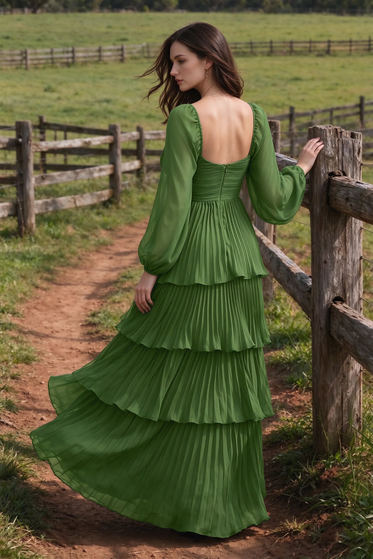 Outdoor rear view by a countryside fence of Sienna basil tiered pleated maxi dress with a long flowing skirt