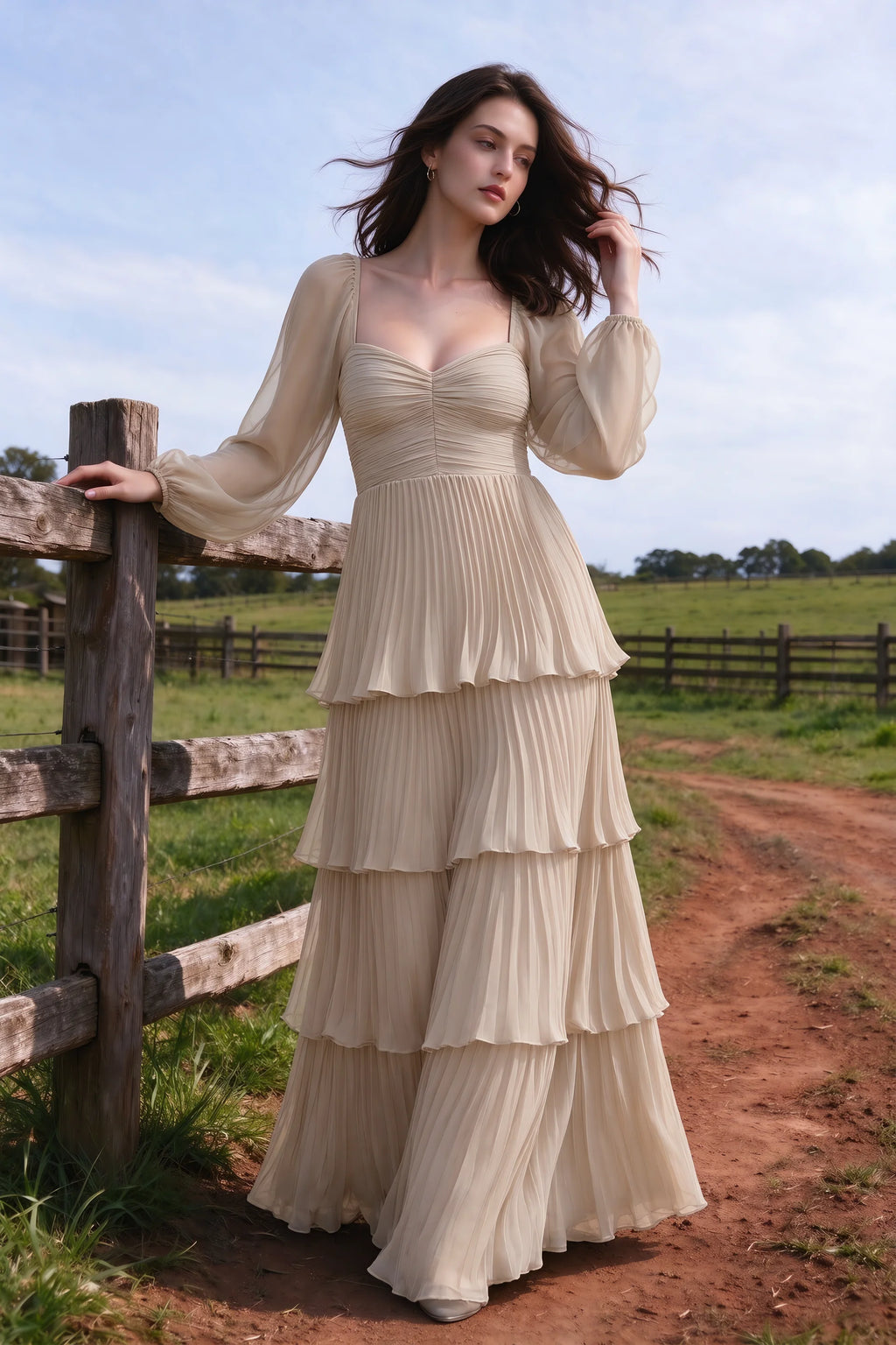 Outdoor front view by a countryside fence of Sienna cream tiered pleated maxi dress with a long flowing skirt