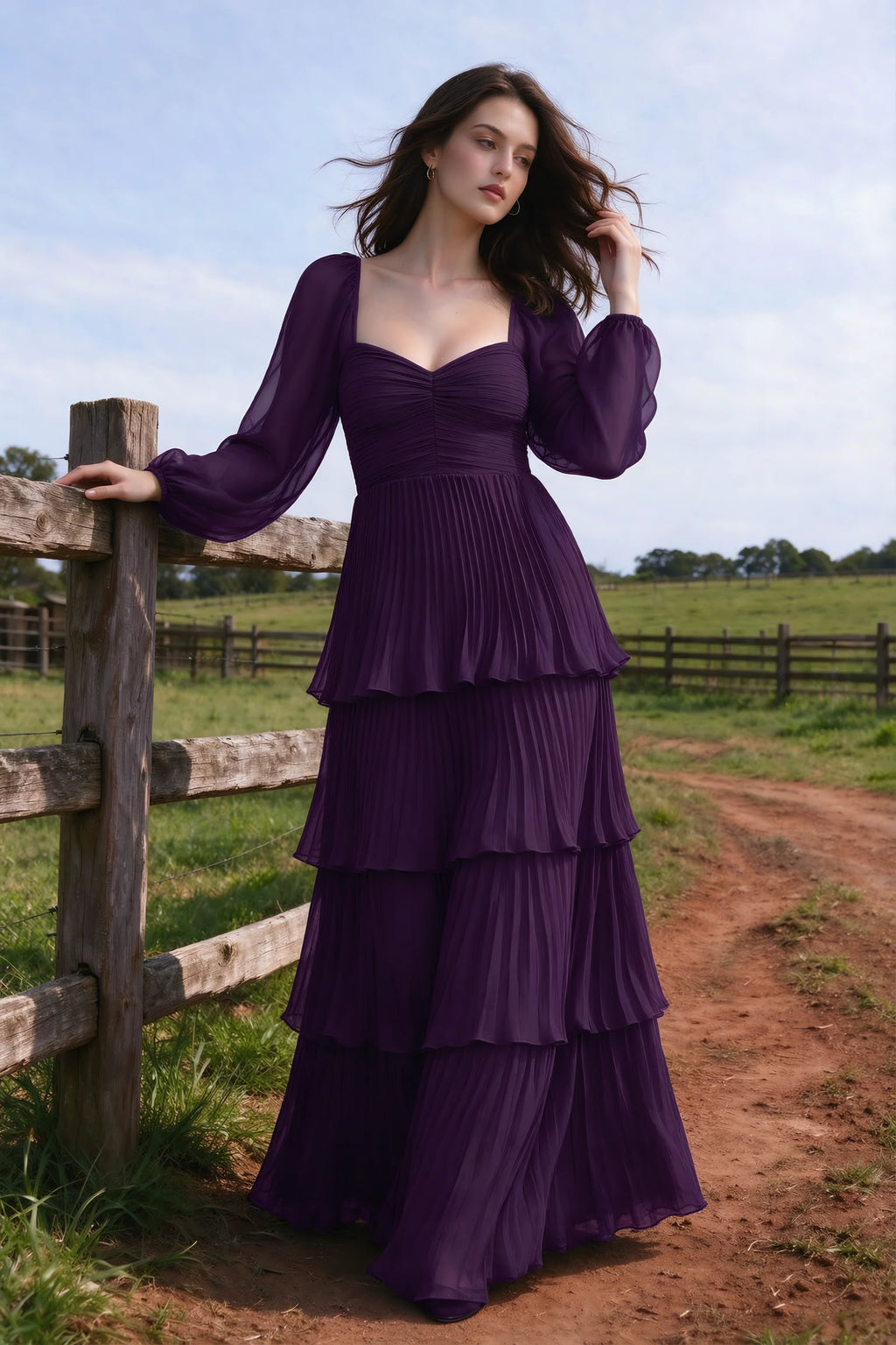 Outdoor front view by a countryside fence of Sienna grape tiered pleated maxi dress with a long flowing skirt