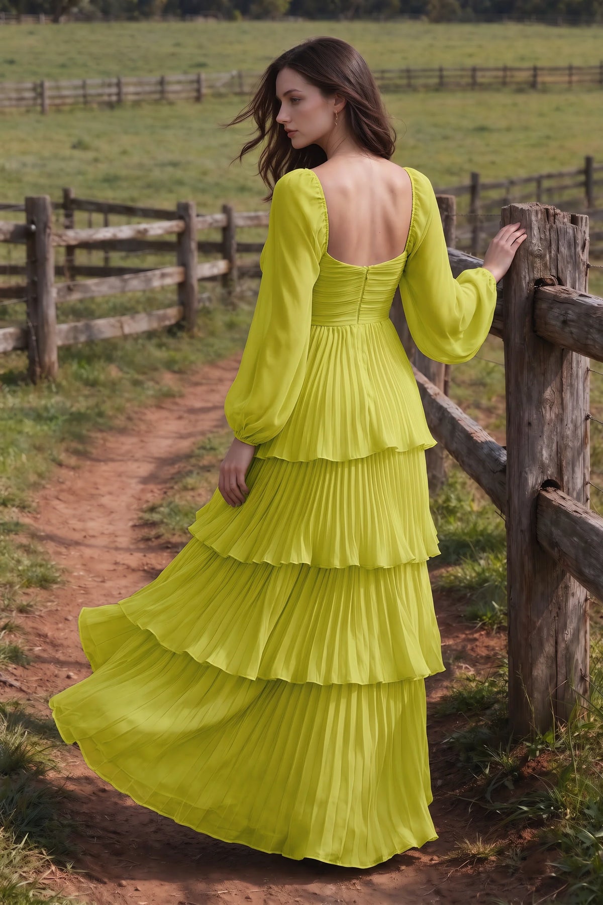 Outdoor rear view by a countryside fence of Sienna lemon green tiered pleated maxi dress with a long flowing skirt