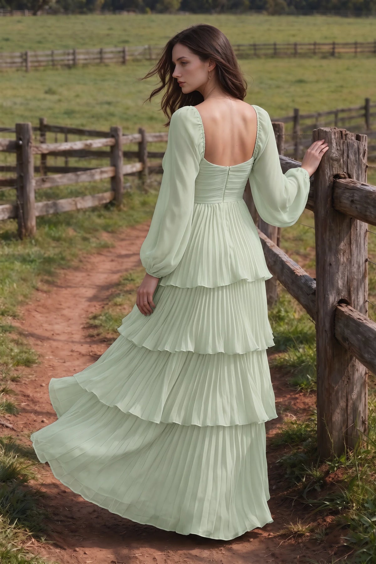 Outdoor rear view by a countryside fence of Sienna light green tiered pleated maxi dress with a long flowing skirt