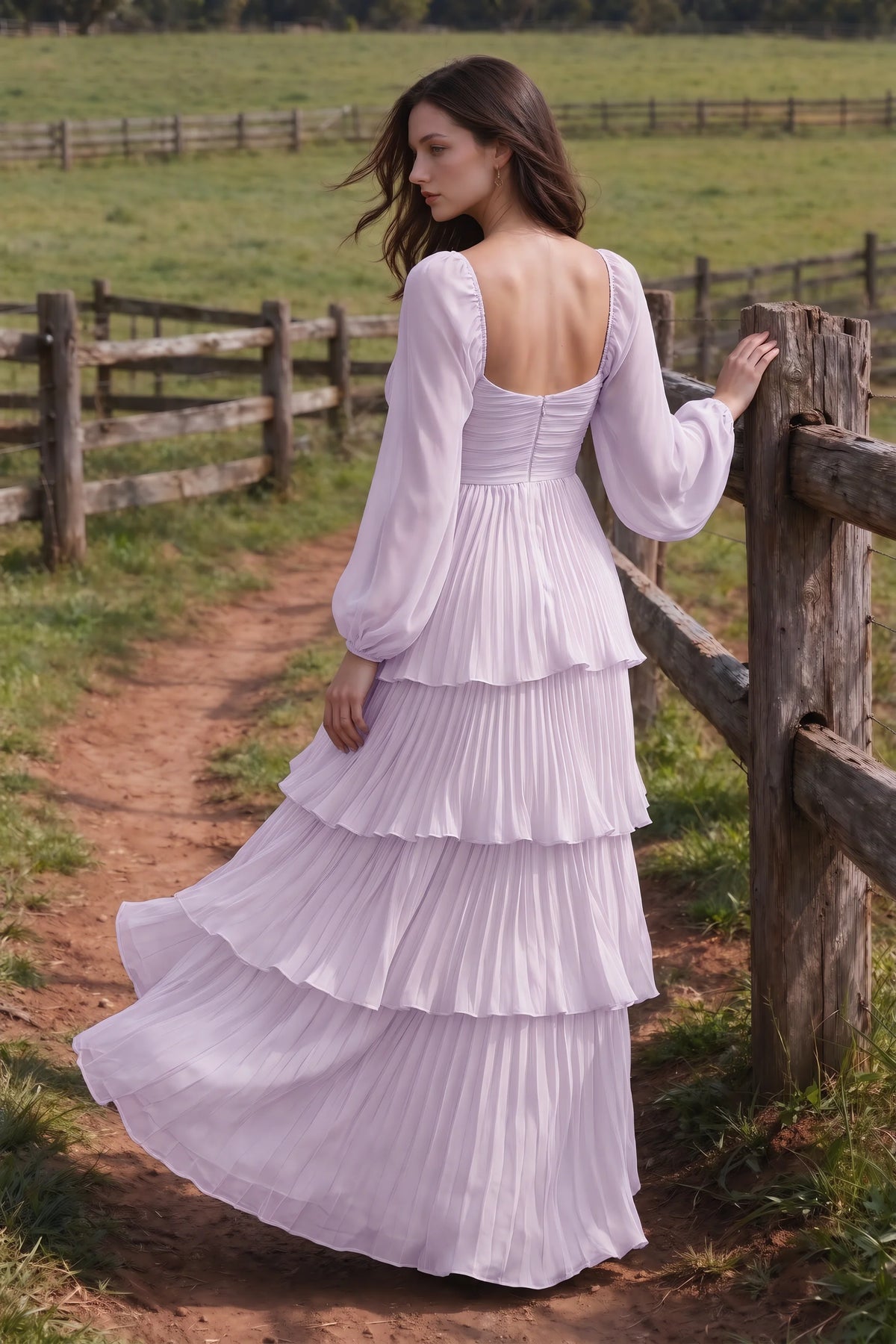 Outdoor rear view by a countryside fence of Sienna lilac tiered pleated maxi dress with a long flowing skirt