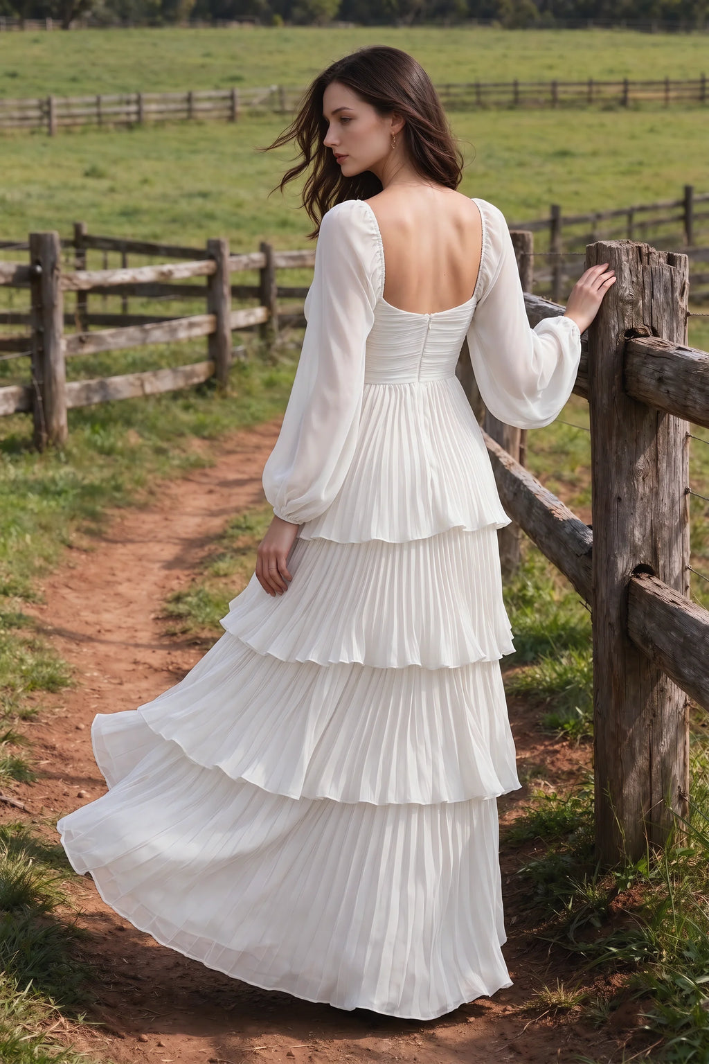 Outdoor rear view by a countryside fence of Sienna white tiered pleated maxi dress with a long flowing skirt