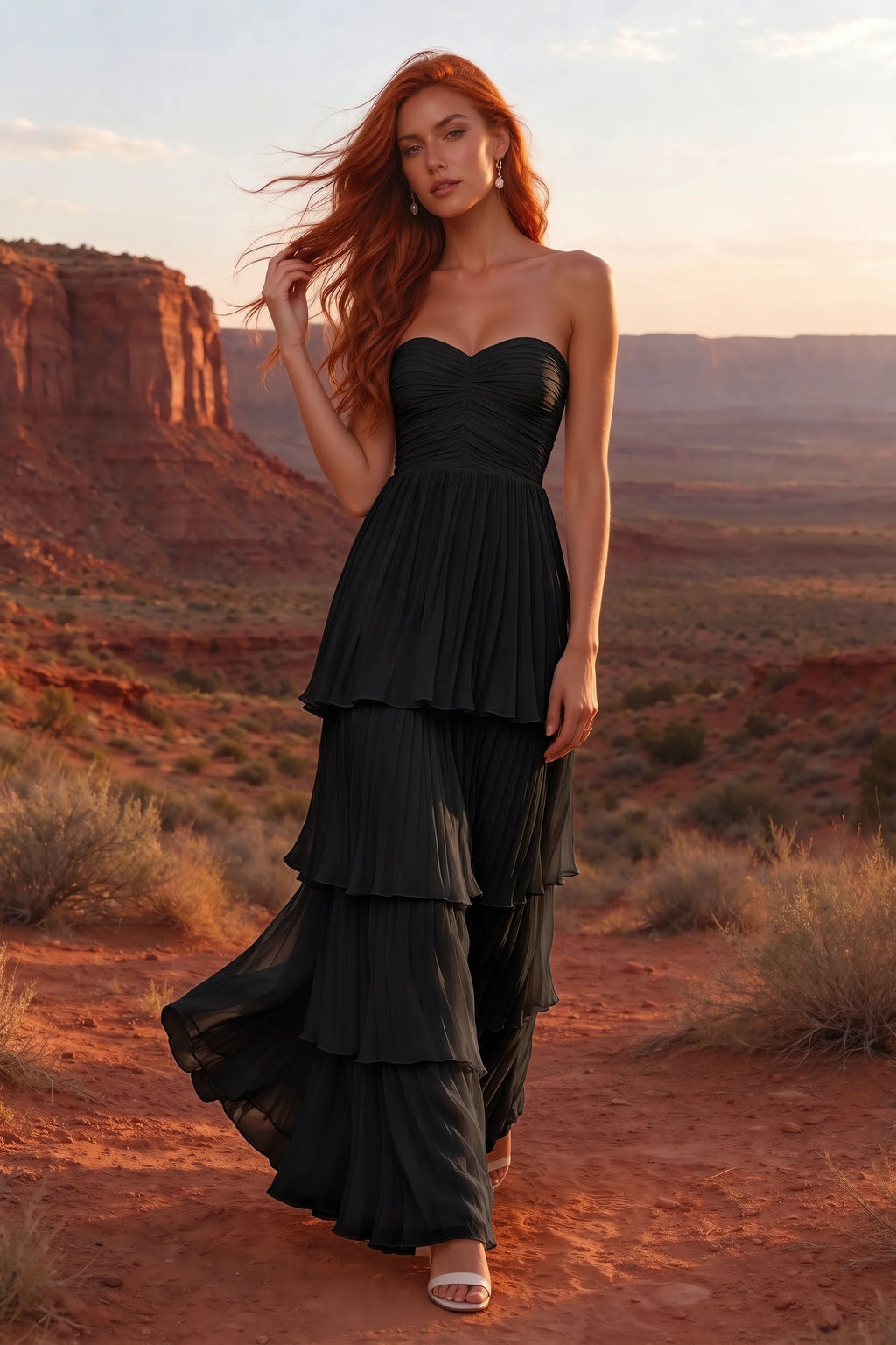 Outdoor front view in a desert canyon at sunset of Sonia black tiered pleated maxi dress with a long flowing skirt