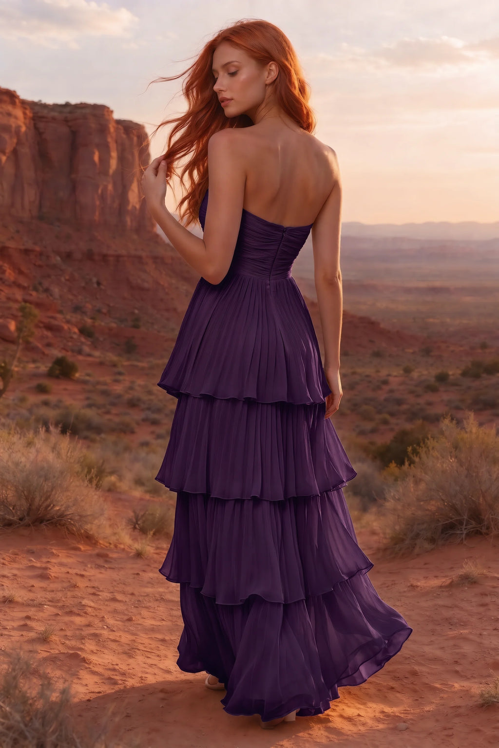 Outdoor rear view in a desert canyon at sunset of Sonia grape tiered pleated maxi dress with a long flowing skirt
