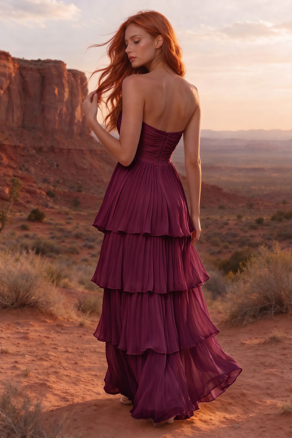 Outdoor rear view in a desert canyon at sunset of Sonia merlot tiered pleated maxi dress with a long flowing skirt