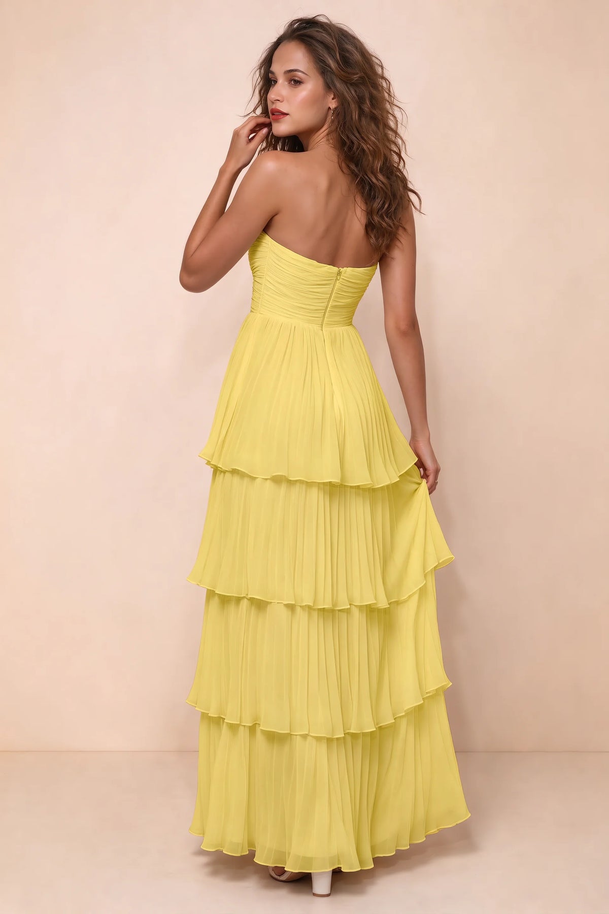 Rear studio view of Sonia pastel yellow tiered pleated maxi dress with a long flowing skirt