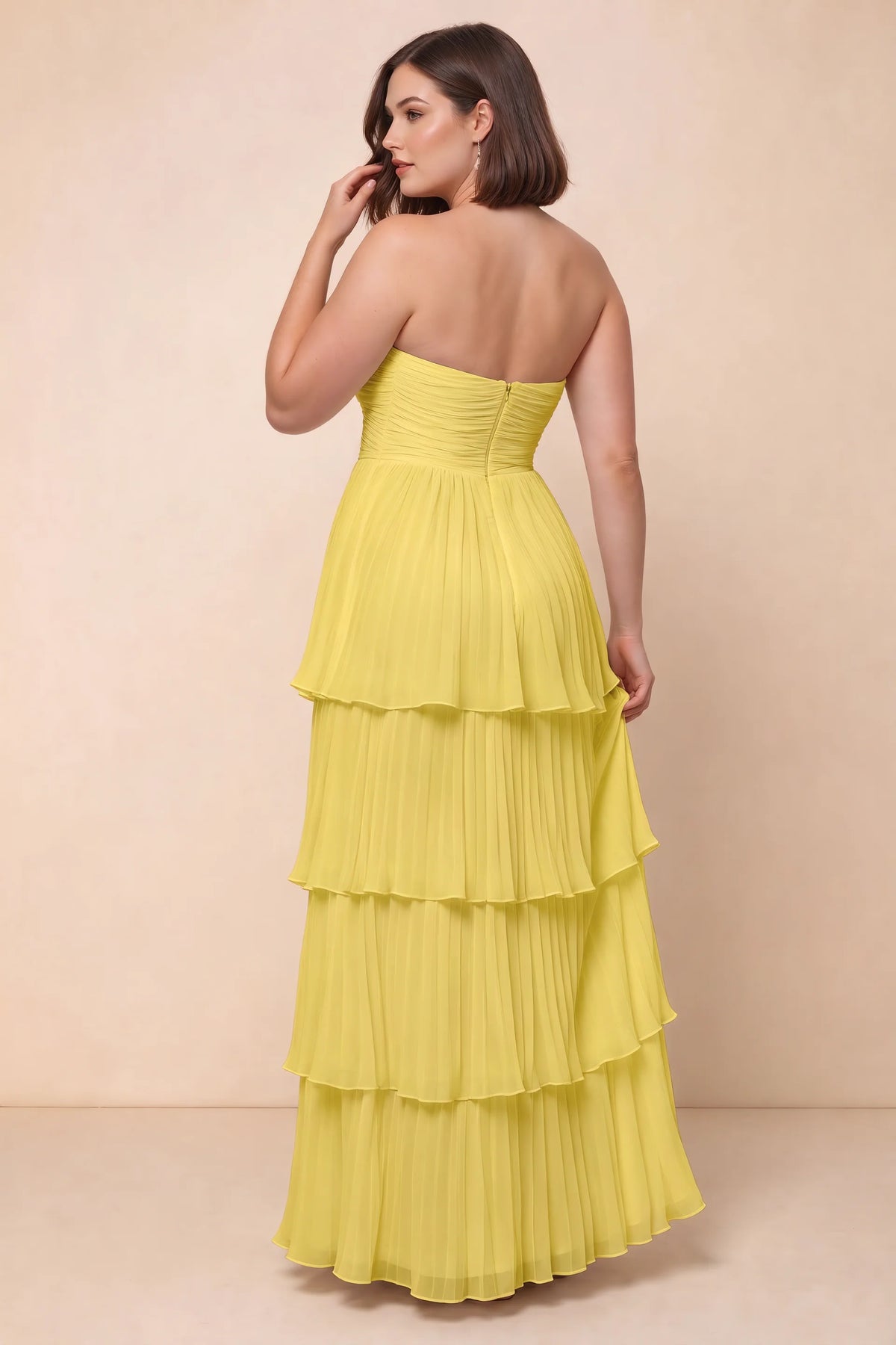 Rear view on a second model of Sonia pastel yellow tiered pleated maxi dress with a long flowing skirt