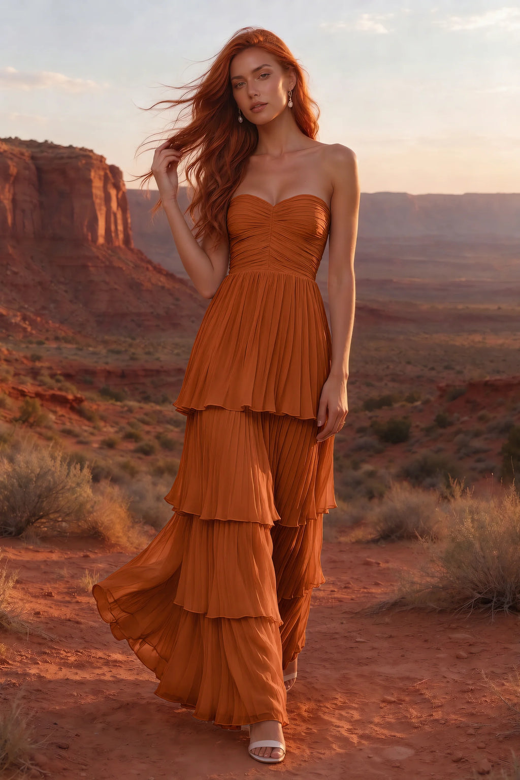 Outdoor front view in a desert canyon at sunset of Sonia rust tiered pleated maxi dress with a long flowing skirt