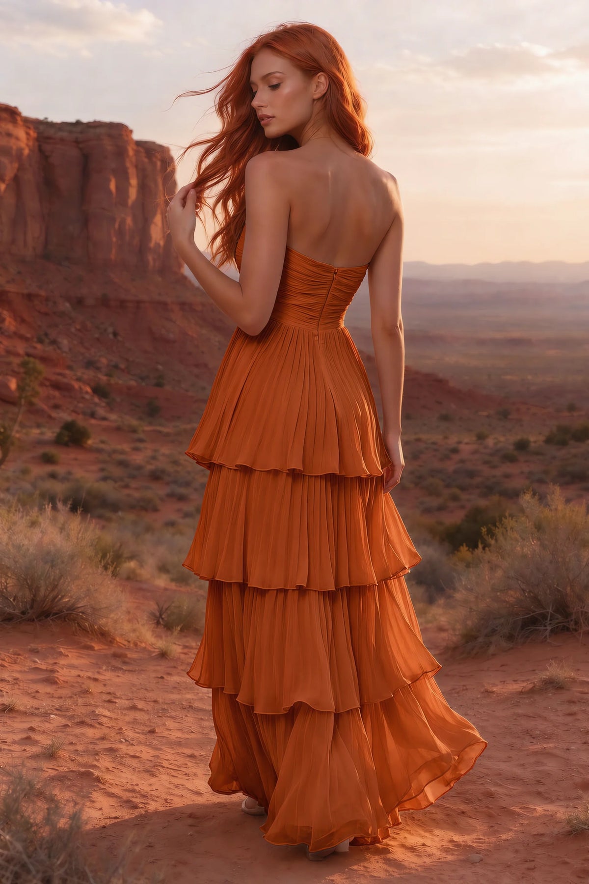 Outdoor rear view in a desert canyon at sunset of Sonia rust tiered pleated maxi dress with a long flowing skirt