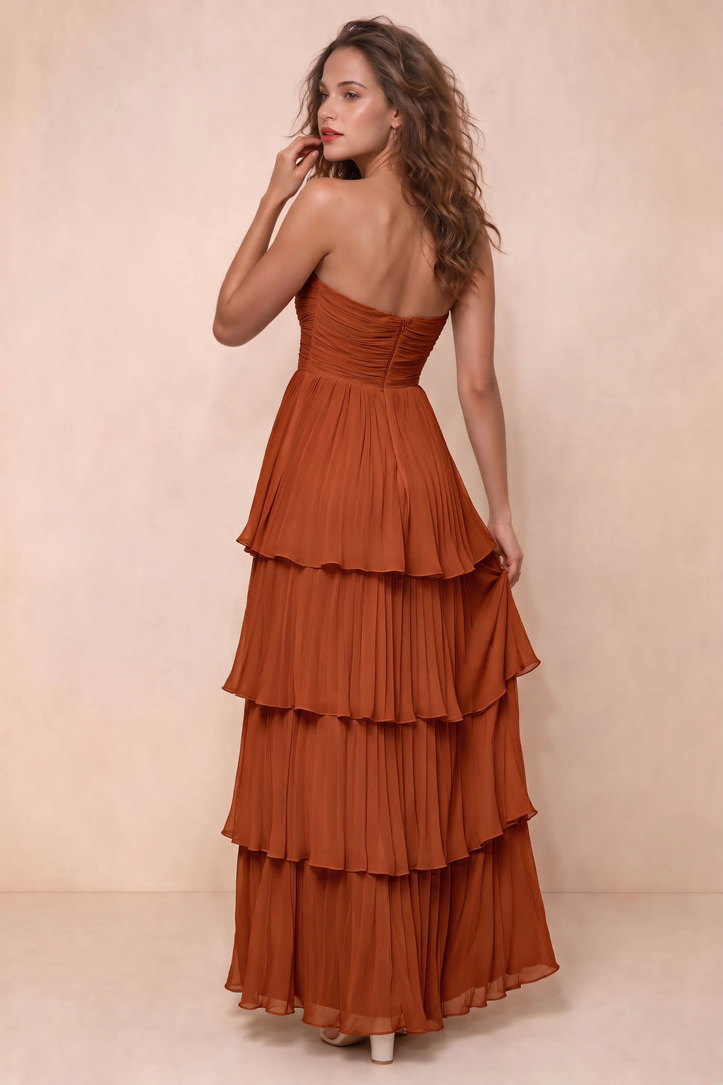 Rear studio view of Sonia rust tiered pleated maxi dress with a long flowing skirt