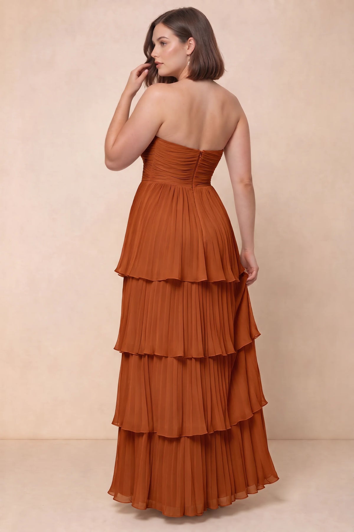 Rear view on a second model of Sonia rust tiered pleated maxi dress with a long flowing skirt