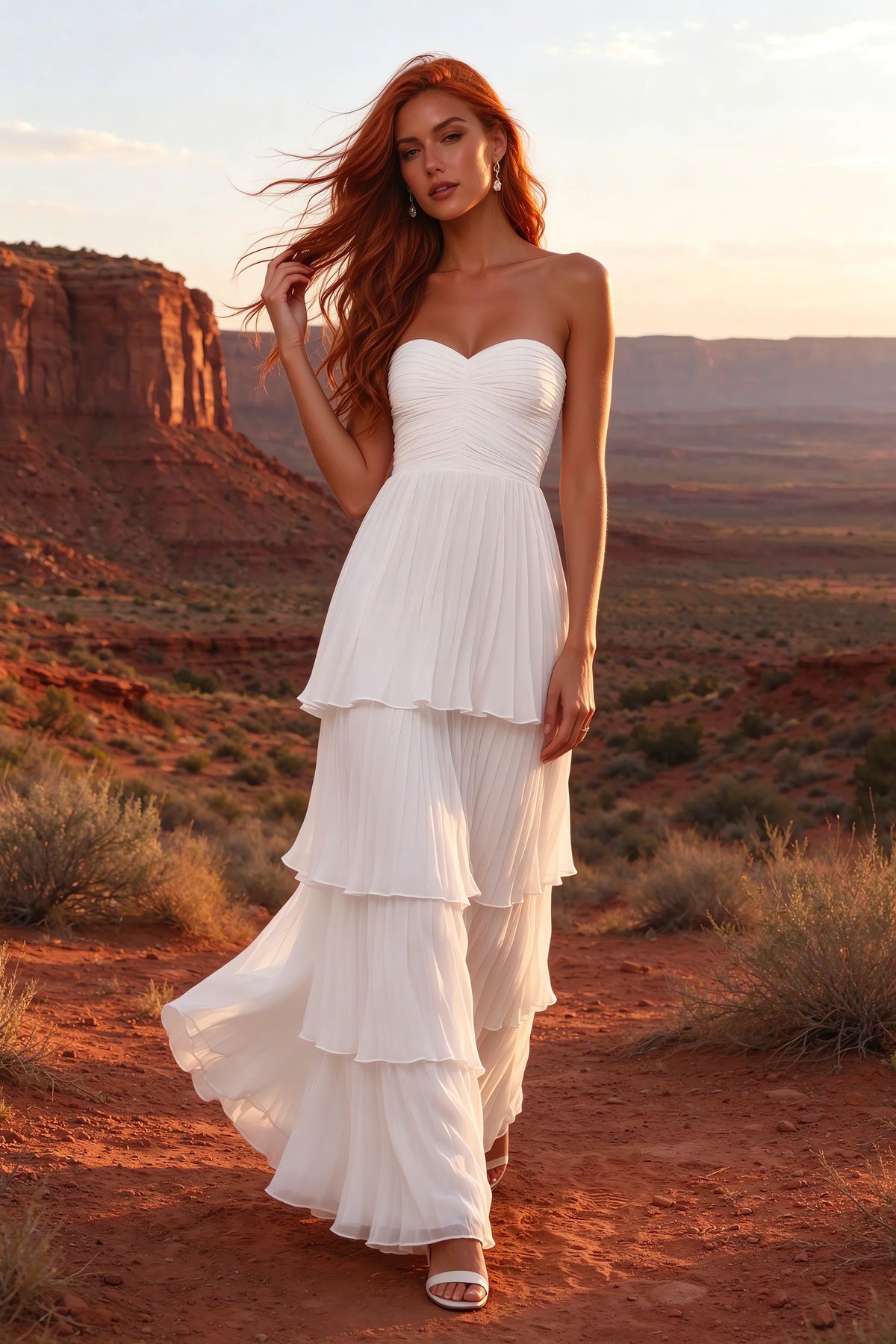 Outdoor front view in a desert canyon at sunset of Sonia white tiered pleated maxi dress with a long flowing skirt