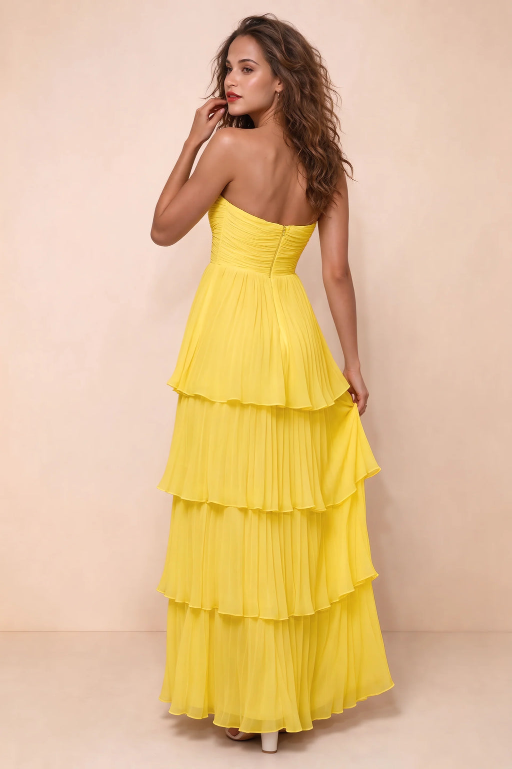 Rear studio view of Sonia yellow tiered pleated maxi dress with a long flowing skirt