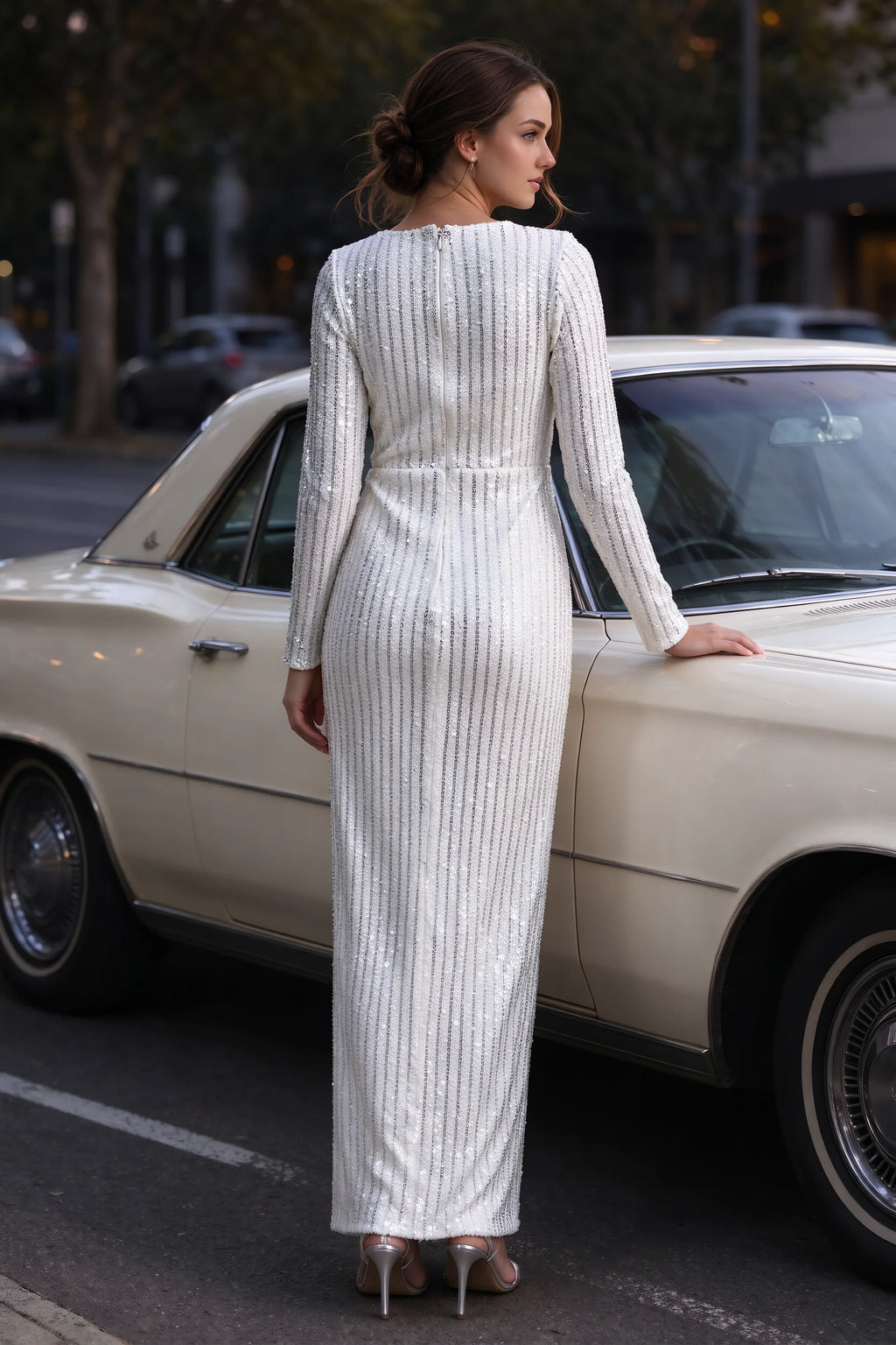 Outdoor rear view beside a classic car of Valeria silver long sleeve V-neck slit maxi dress with a long straight skirt